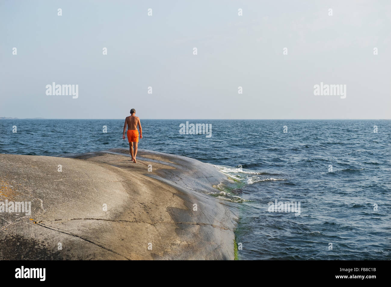 Sweden, Stockholms Archipelago, Sodermanland, Haninge, Norsten, Man walking along sea Stock Photo