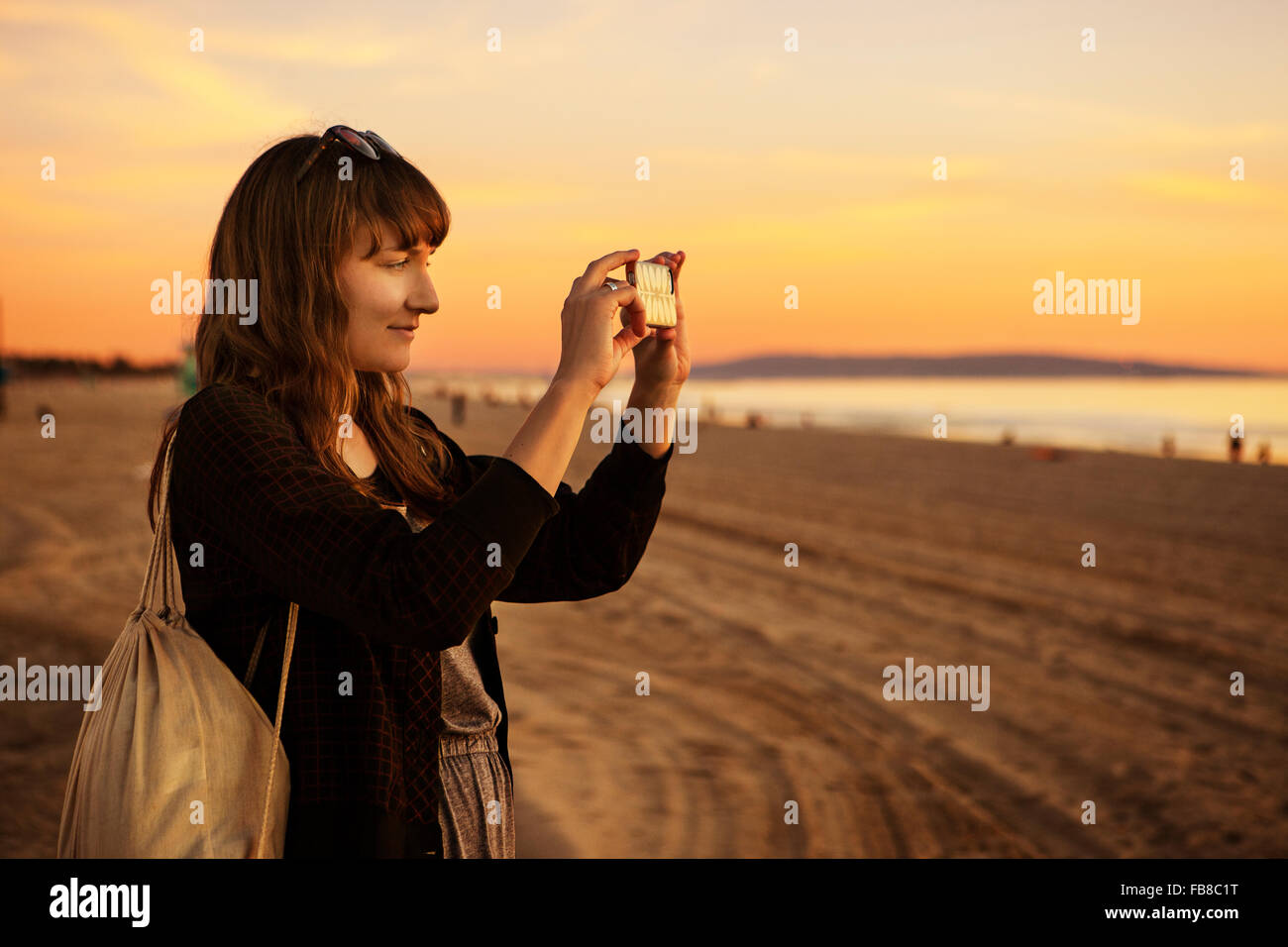 USA, California, Los Angeles, Santa Monica, Mid adult woman photographing at sunset Stock Photo