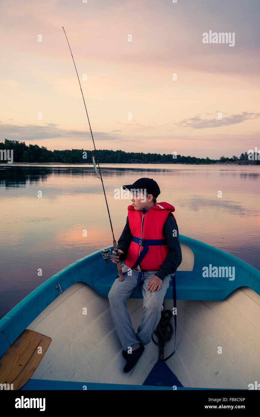 Sweden, Smaland, Tjust archipelago, Vastervik, Hasselo, Boy (10-11) fly fishing in boat on lake Stock Photo
