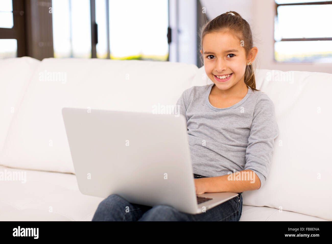 beautiful little girl using laptop on sofa at home Stock Photo - Alamy
