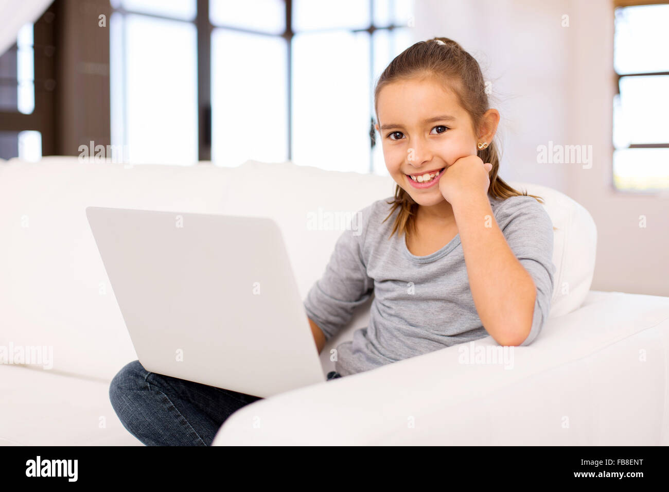 portrait of pretty little girl using laptop at home Stock Photo - Alamy