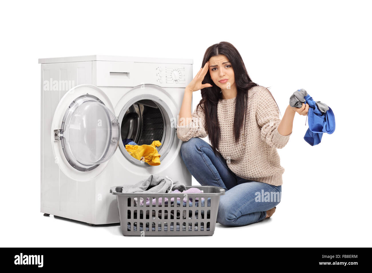 Studio shot of a sad woman emptying a washing machine and looking at the camera isolated on white background Stock Photo