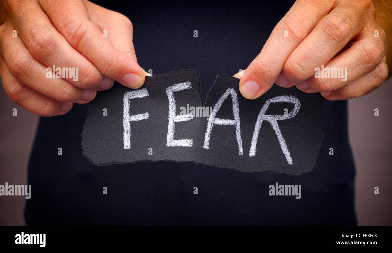 Woman ripping Fear word written on black paper. Close up. Stock Photo