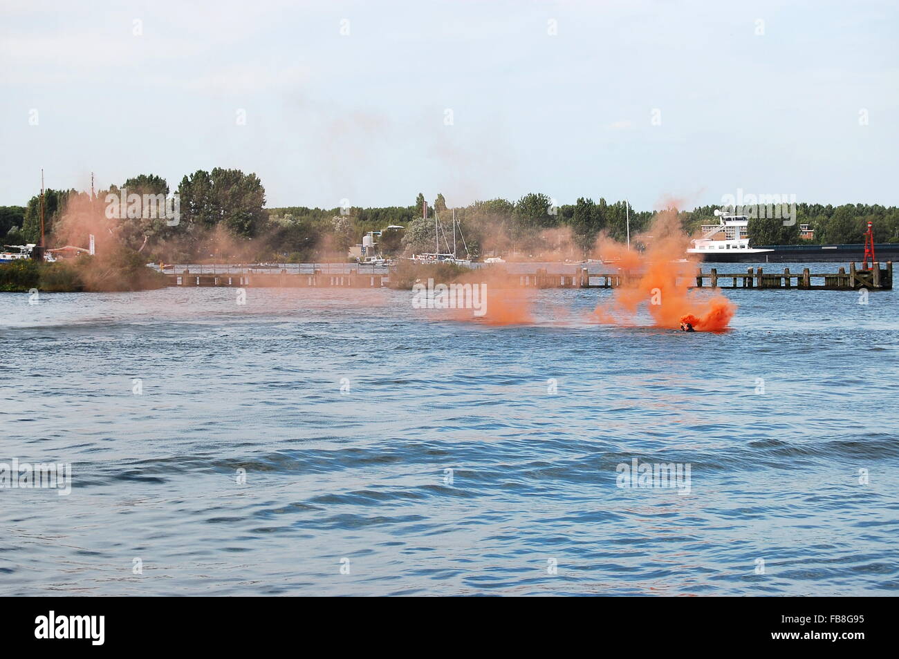 Swimmer with an orange flare during a demonstration at Sail Amsterdam 2010 Stock Photo