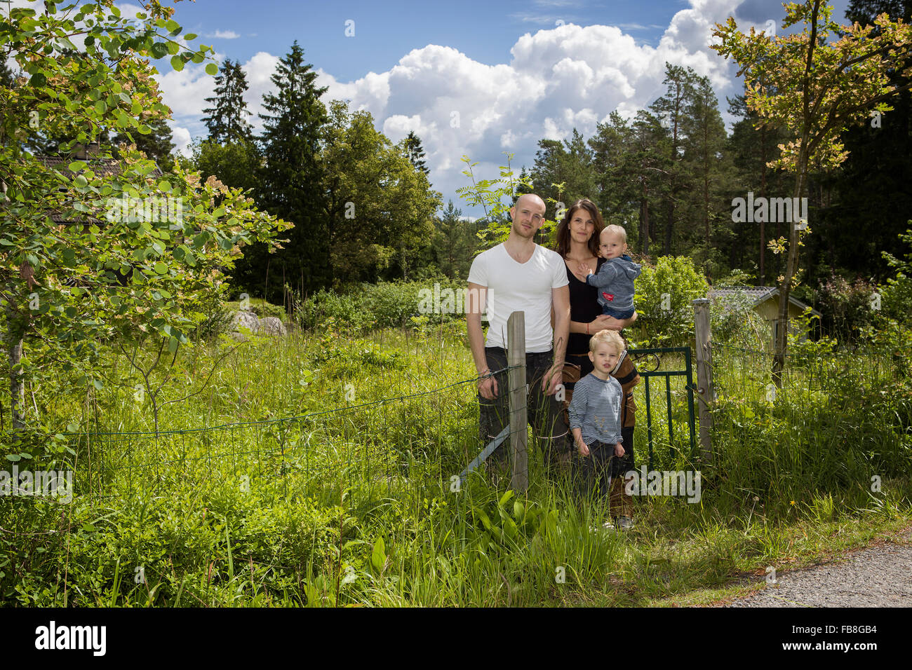 Sweden, Stockholm, Uppland, Nacka, Family with two children (18-23 months, 4-5) standing among lush foliage Stock Photo