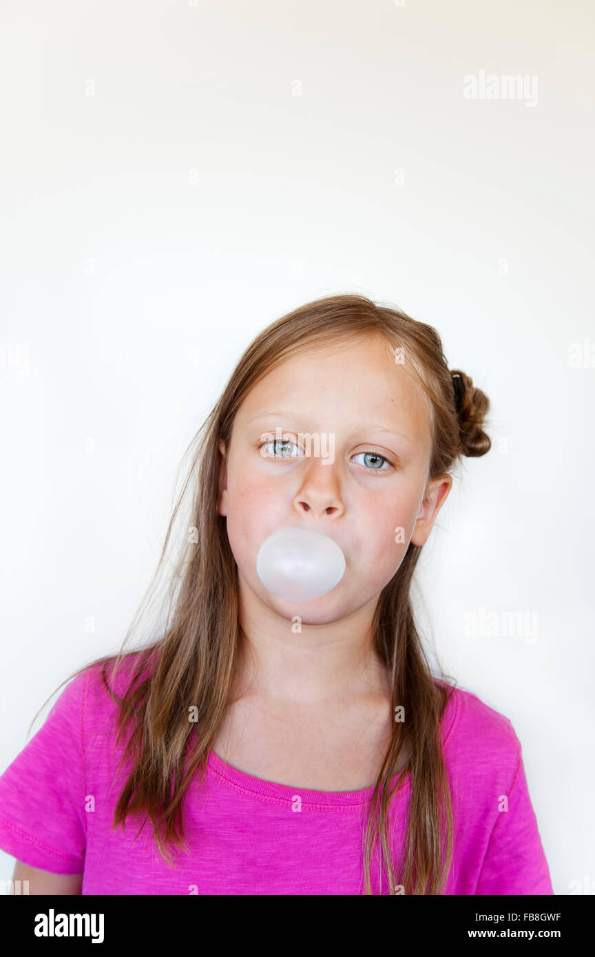 Girl (6-7) blowing bubblegum Stock Photo