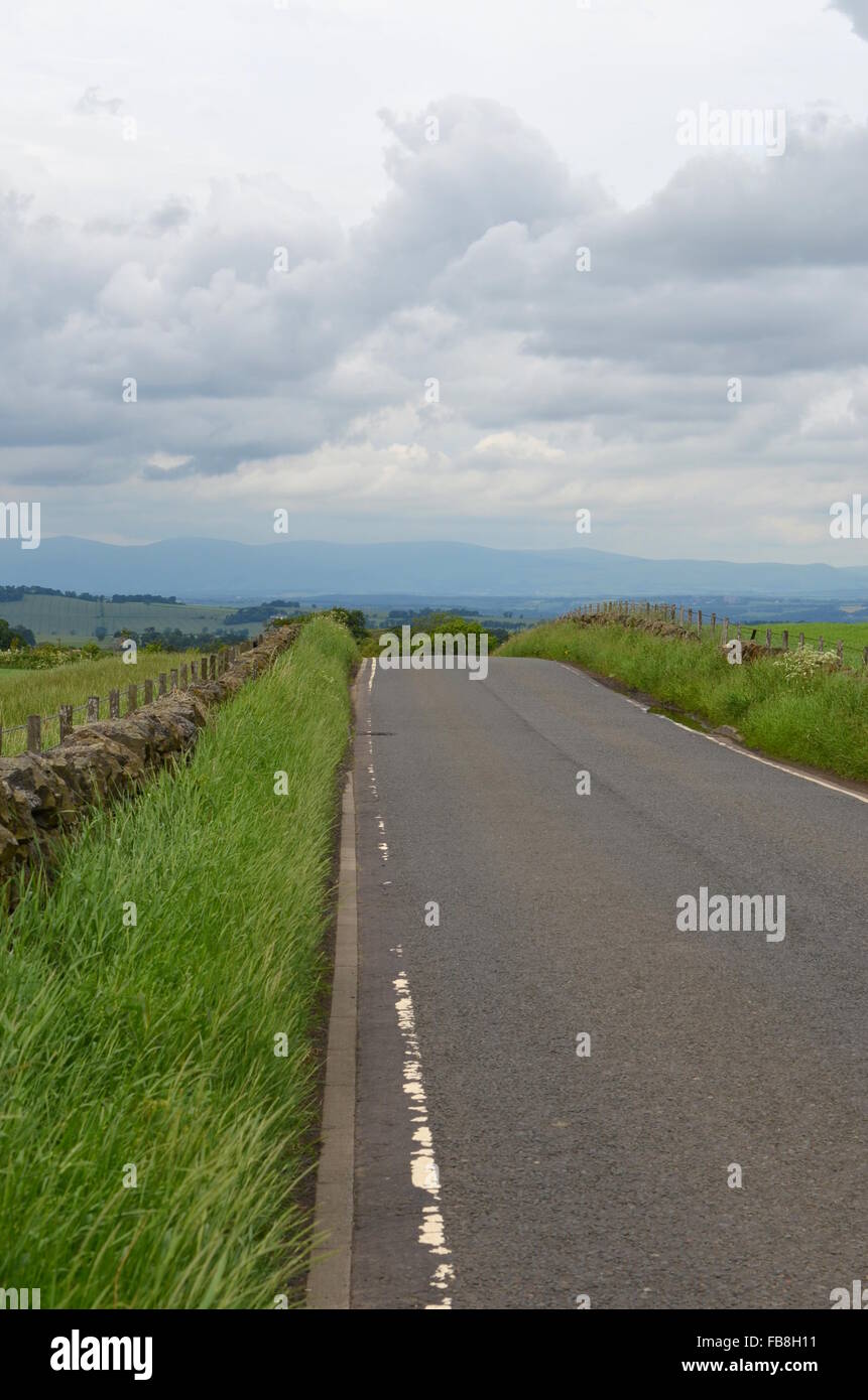 Road downhill towards hills in the distance, West Lothian, Scotland Stock Photo