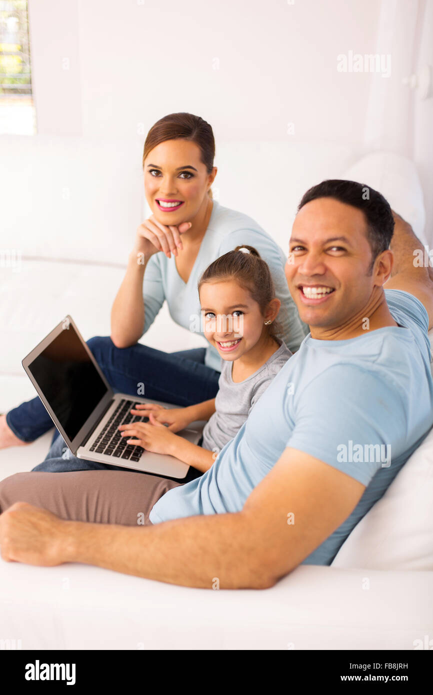 happy family of three using laptop computer while relaxing on sofa at ...
