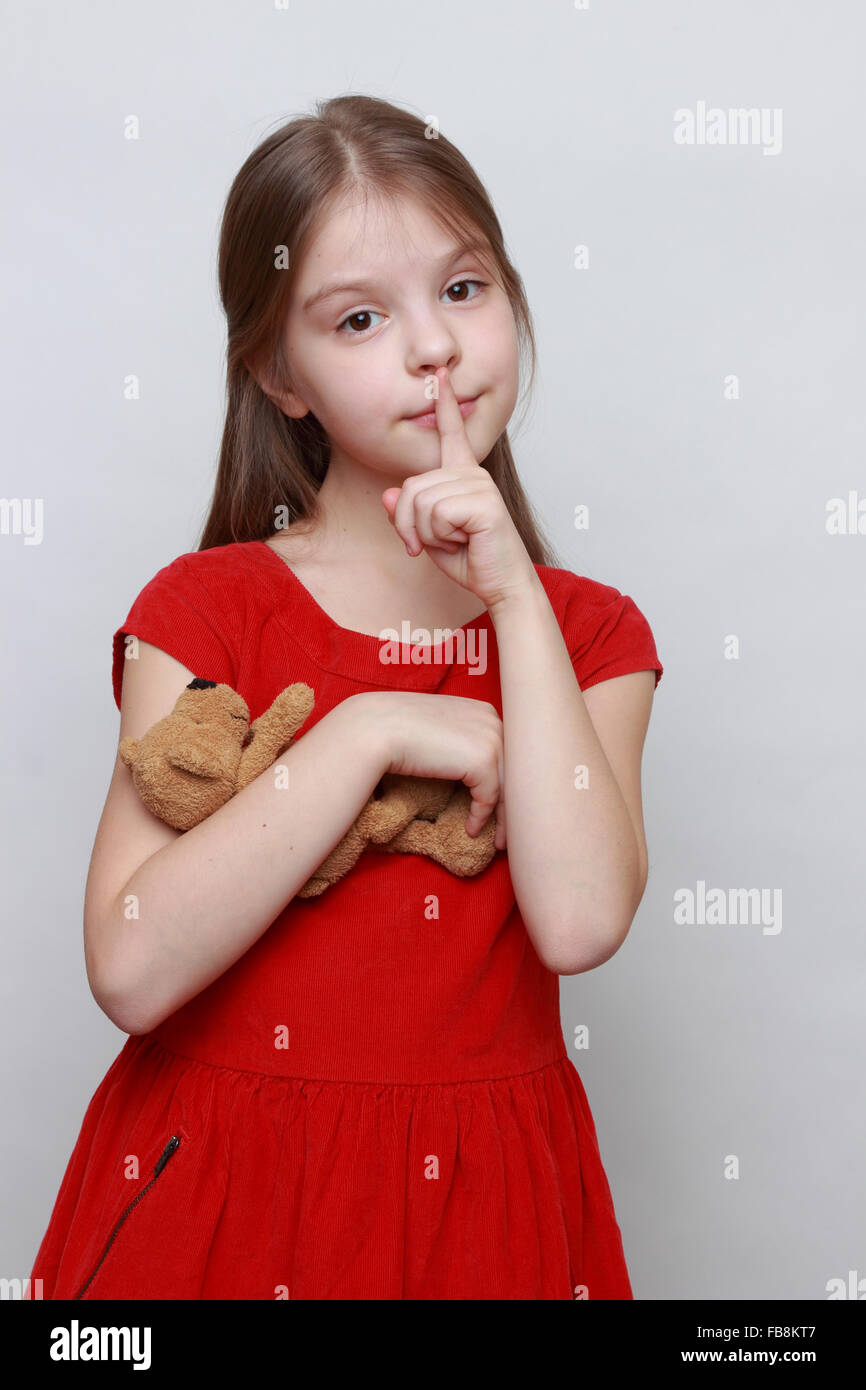 Beautiful little girl in red fashion dress holding lovely toy teddy bear Stock Photo