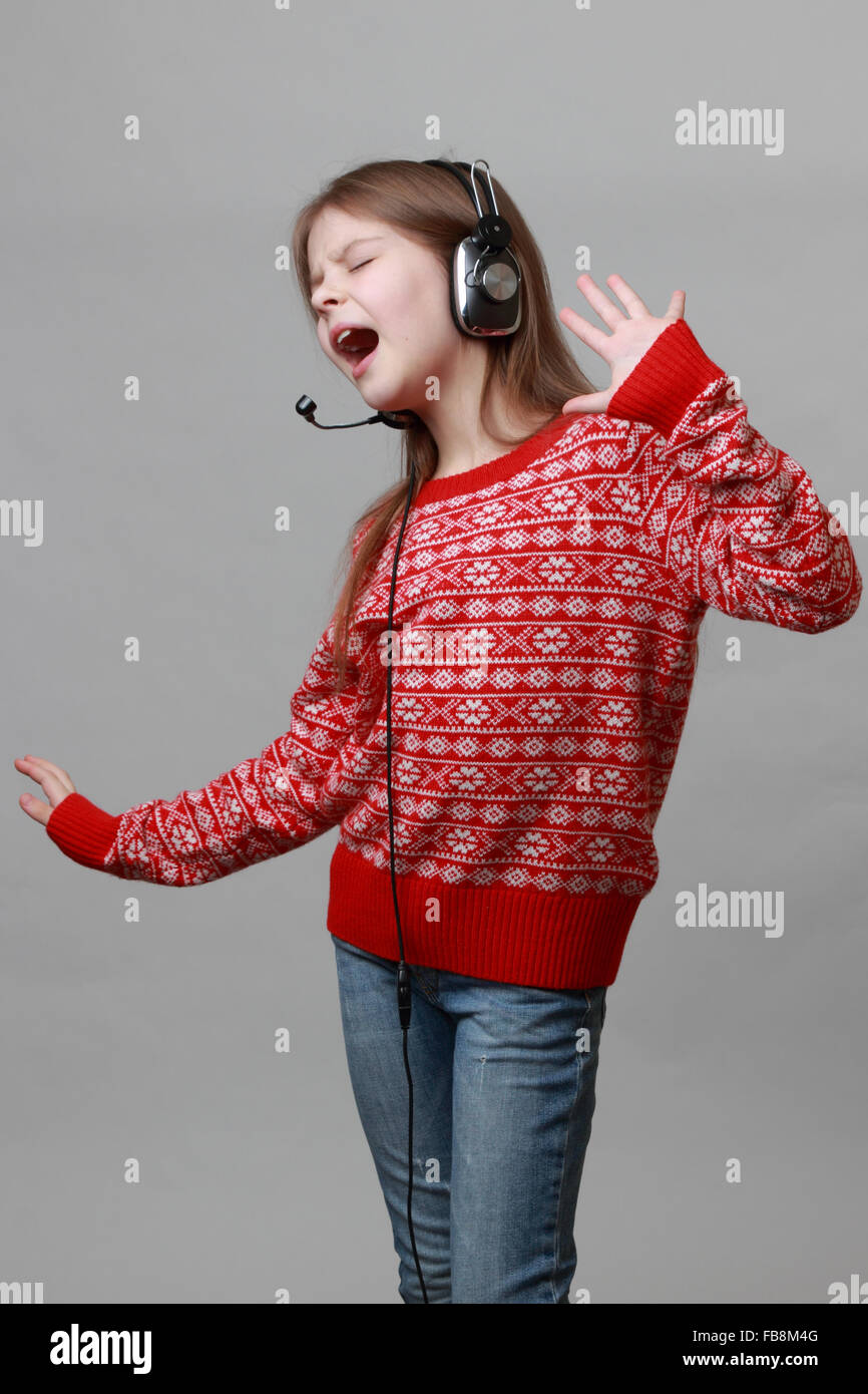 Lovely caucasian little girl wearing red Christmas sweater is singing Stock Photo