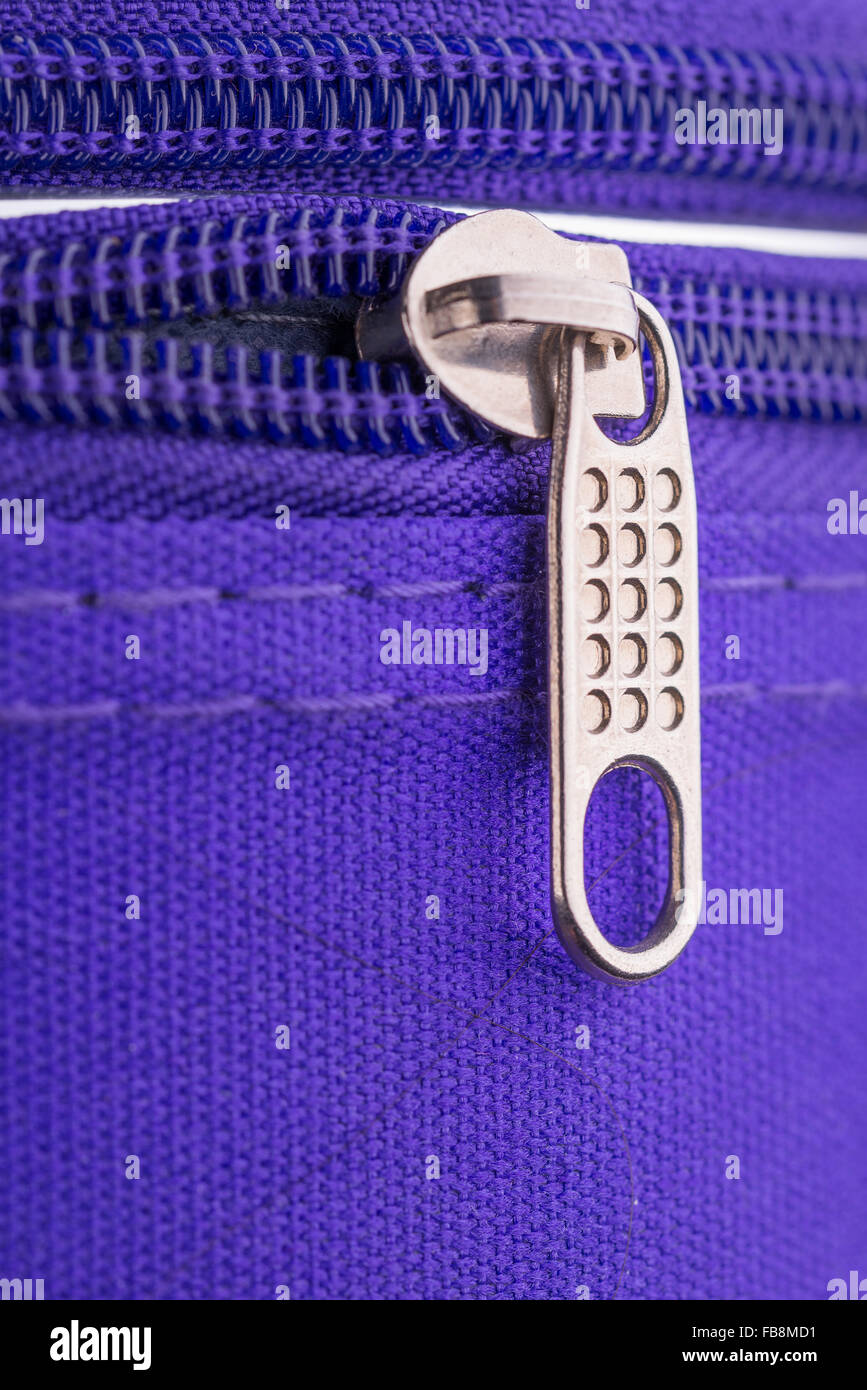 Macro of a zipper showing the pull tab and the chain on a violet suitcase ready for a safe holiday travel Stock Photo