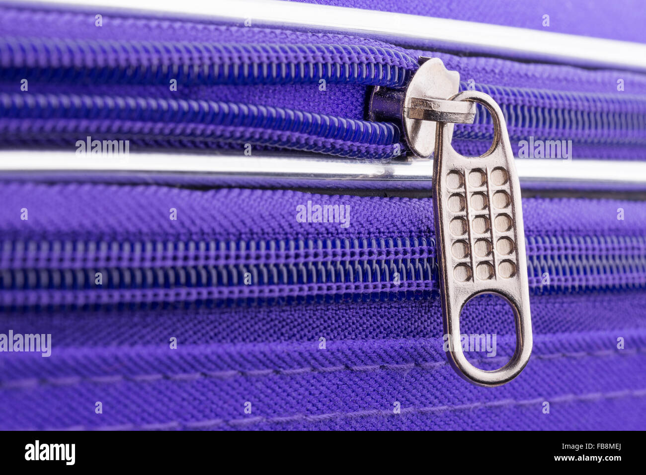 Macro of a zipper showing the pull tab and the chain on a violet suitcase ready for a safe holiday travel Stock Photo