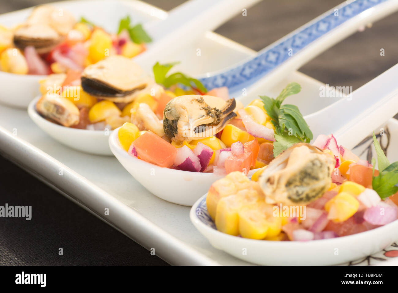 Peruvian ceviche made with mussels on ceramic serving spoons Stock