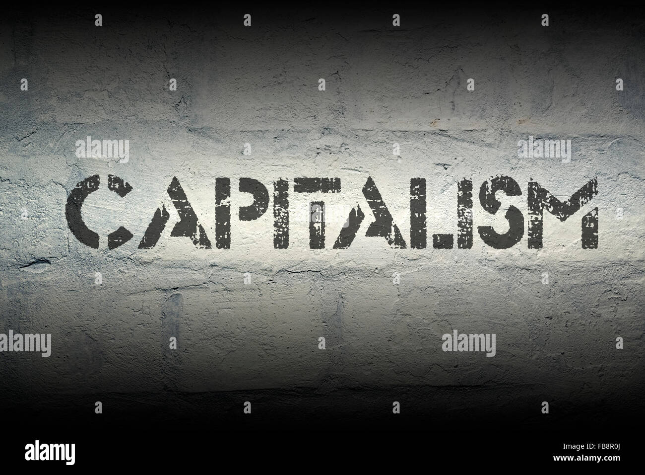 capitalism word stencil print on the grunge white brick wall Stock Photo