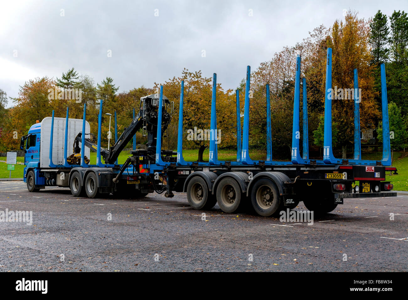 A specialist trailer for carrying huge logs and tree trunks. The lorry has it's own hiab for lifting logs onto the trailer. Stock Photo