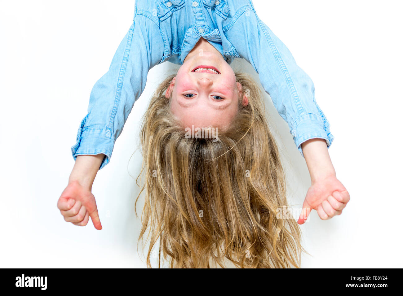 Smiling young girl hanging in front of white background Stock Photo