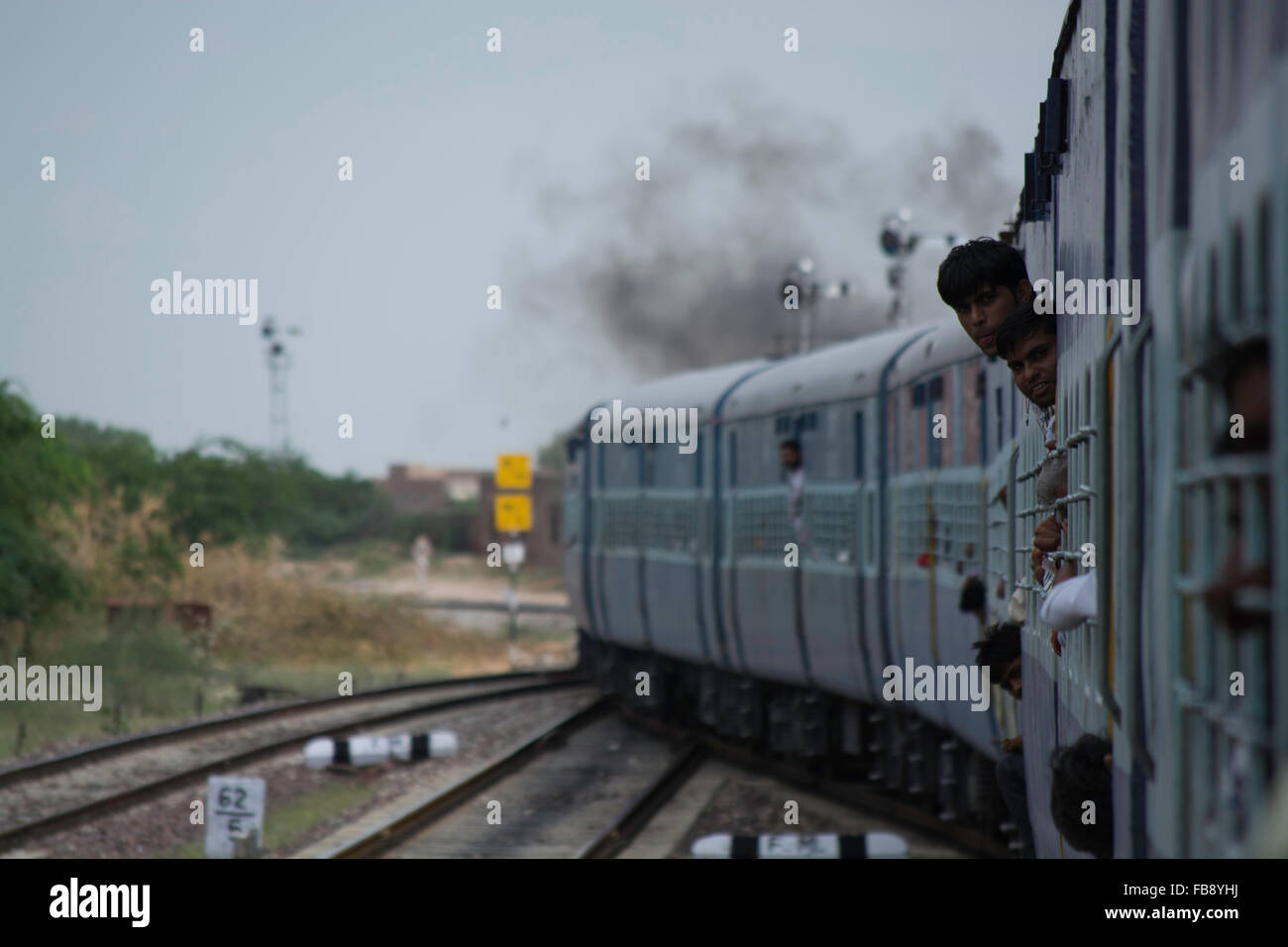 Passengers looking/pointing out of crowded train. Indian Railways, India. Stock Photo