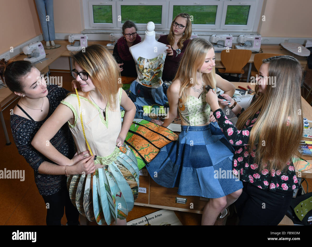 Bad Lauchstaedt, Germany. 11th Jan, 2016. Pupils Anne Michalsky (l) and Lea Recha (r) arrange fellow pupils and models Alina Raue (2.f.r.) and Lydia Ulrich at the Goethe Schule in Bad Lauchstaedt, Germany, 11 January 2016. Under the direction of the Schule fuer Mode und Design fashion school in Magdeburg, the pupils are making clothes for Fashion Week. The 40-minute show is due to take place in Berlin on 17 January. Photo: Hendrik Schmidt/ZB/dpa/Alamy Live News Stock Photo