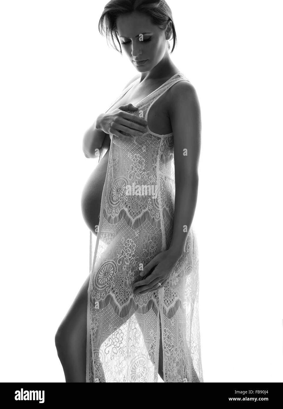 Beautiful pregnant model in black and white with see through lace dress gown in studio. Bump shot of woman Stock Photo