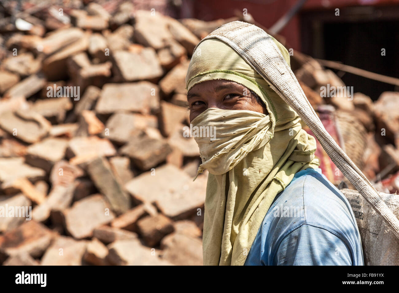 earthquake reconstruction worker in Kathmandu wearing a dust mask and carrying a sack of rubble Stock Photo