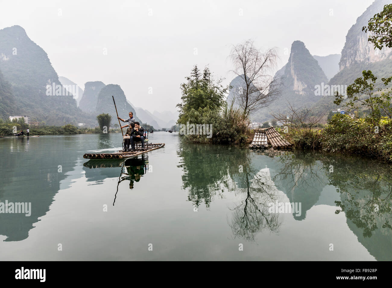 Yulong River, Yangshuo - China. January 2016 - People traveling along the Yulong river on top of traditional bamboo rafts. Stock Photo