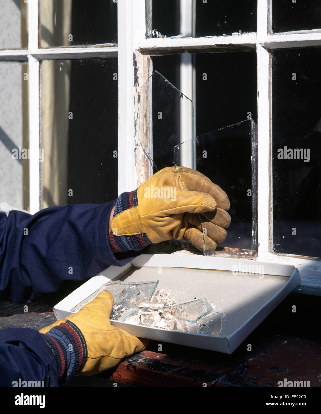 Close-up of hands knocking out broken window glass from a frame Stock Photo