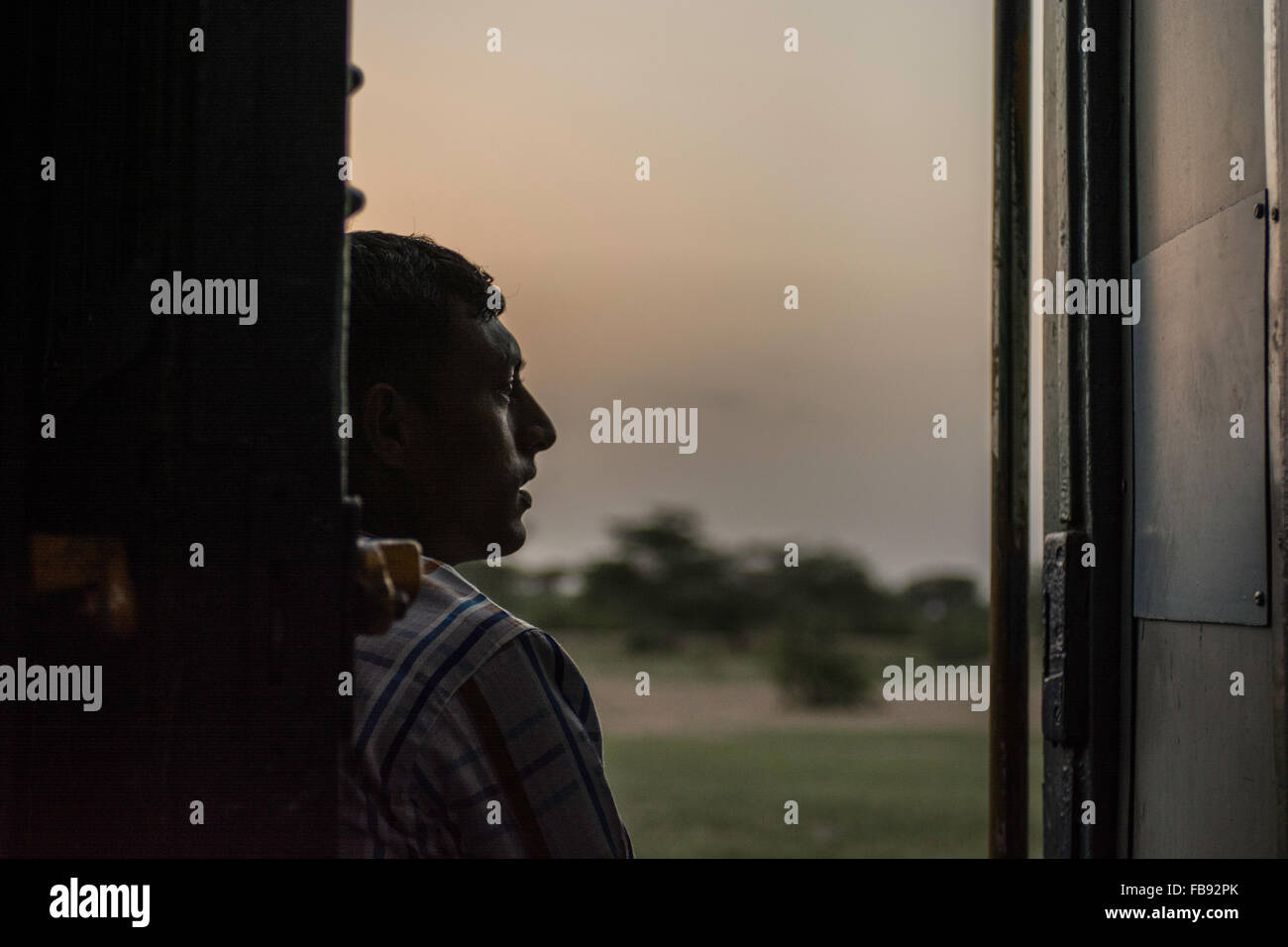 Passenger looking out of train at sunset. Indian Railways, Rajasthan, India, Stock Photo