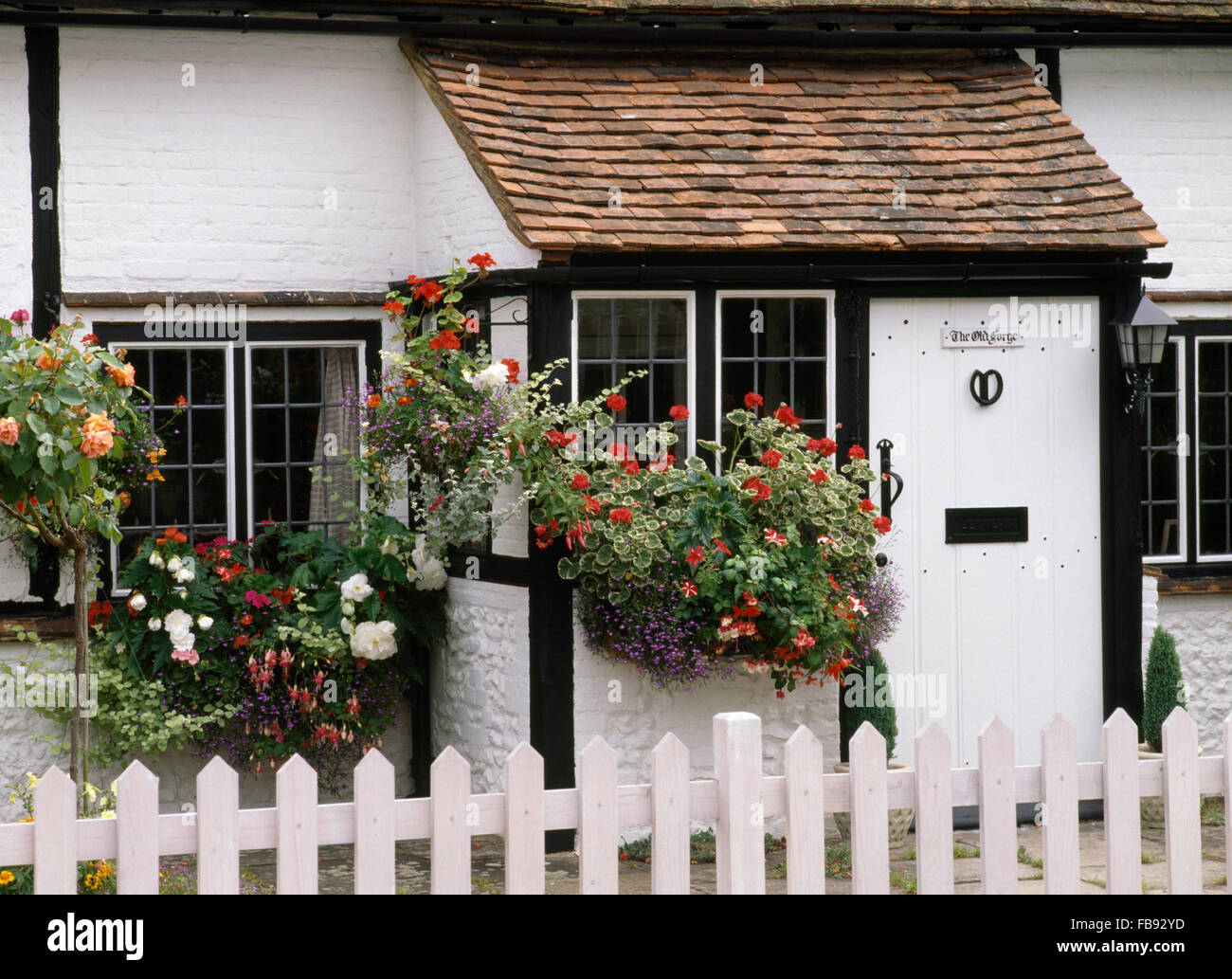 Exterior of a black+white timbered cottage with hanging baskets Stock Photo