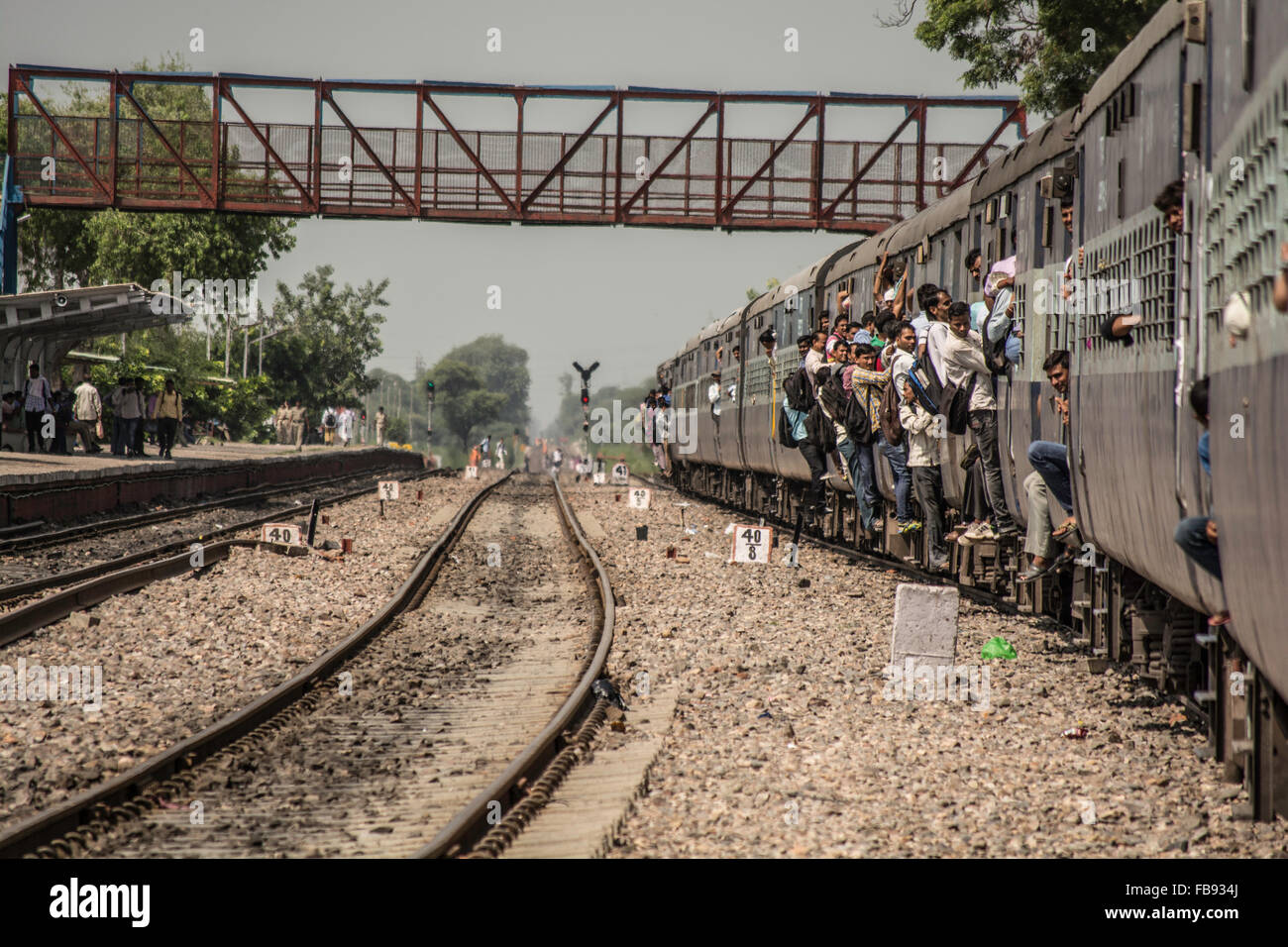 Passengers hanging off overcrowded train near New Delhi, India. Stock Photo