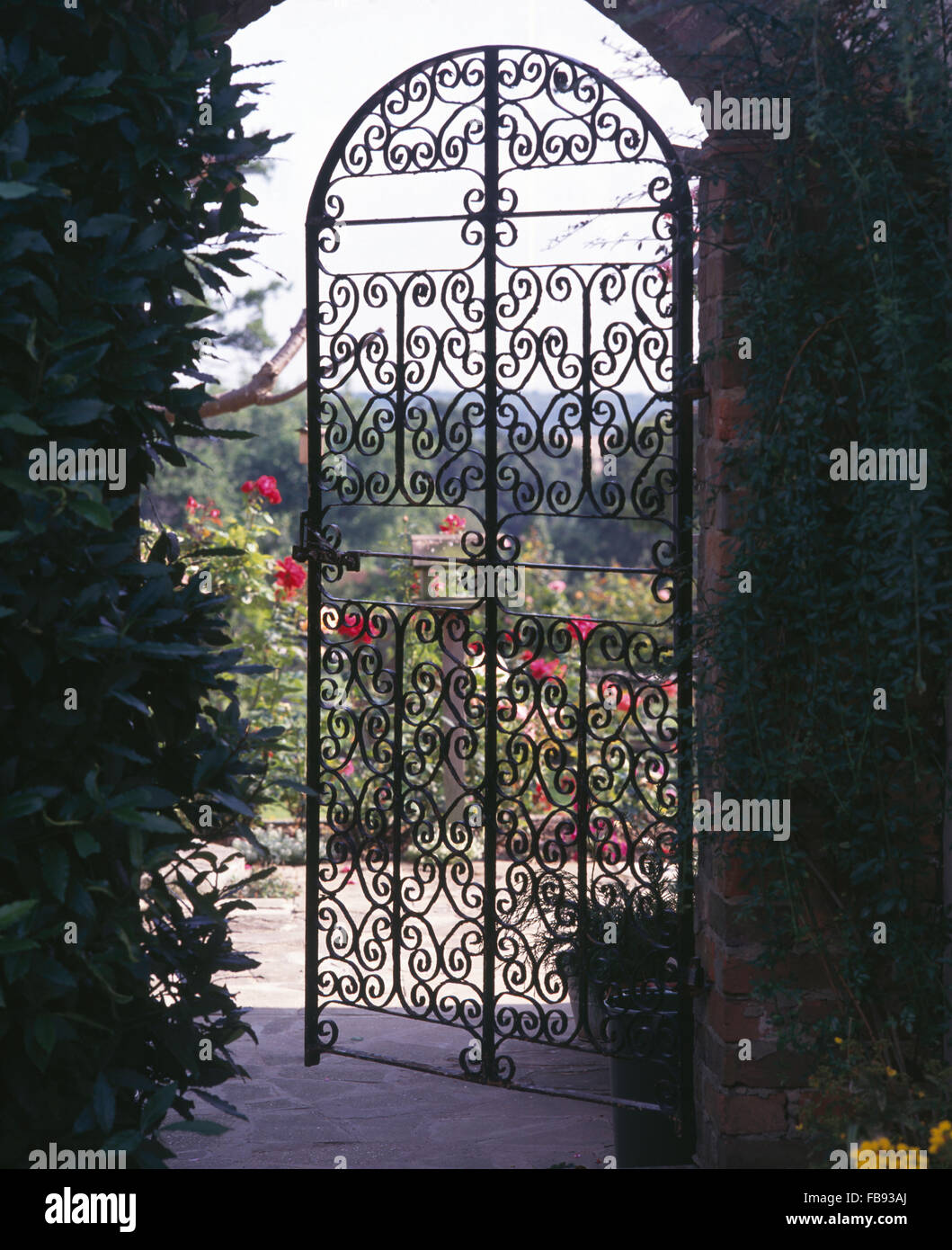 View of a country garden through a wrought iron gate Stock Photo