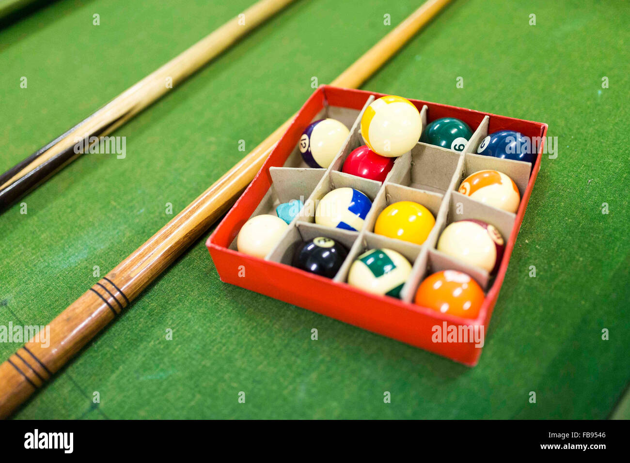pool balls and cues on a pool table at a community centre in England Stock Photo