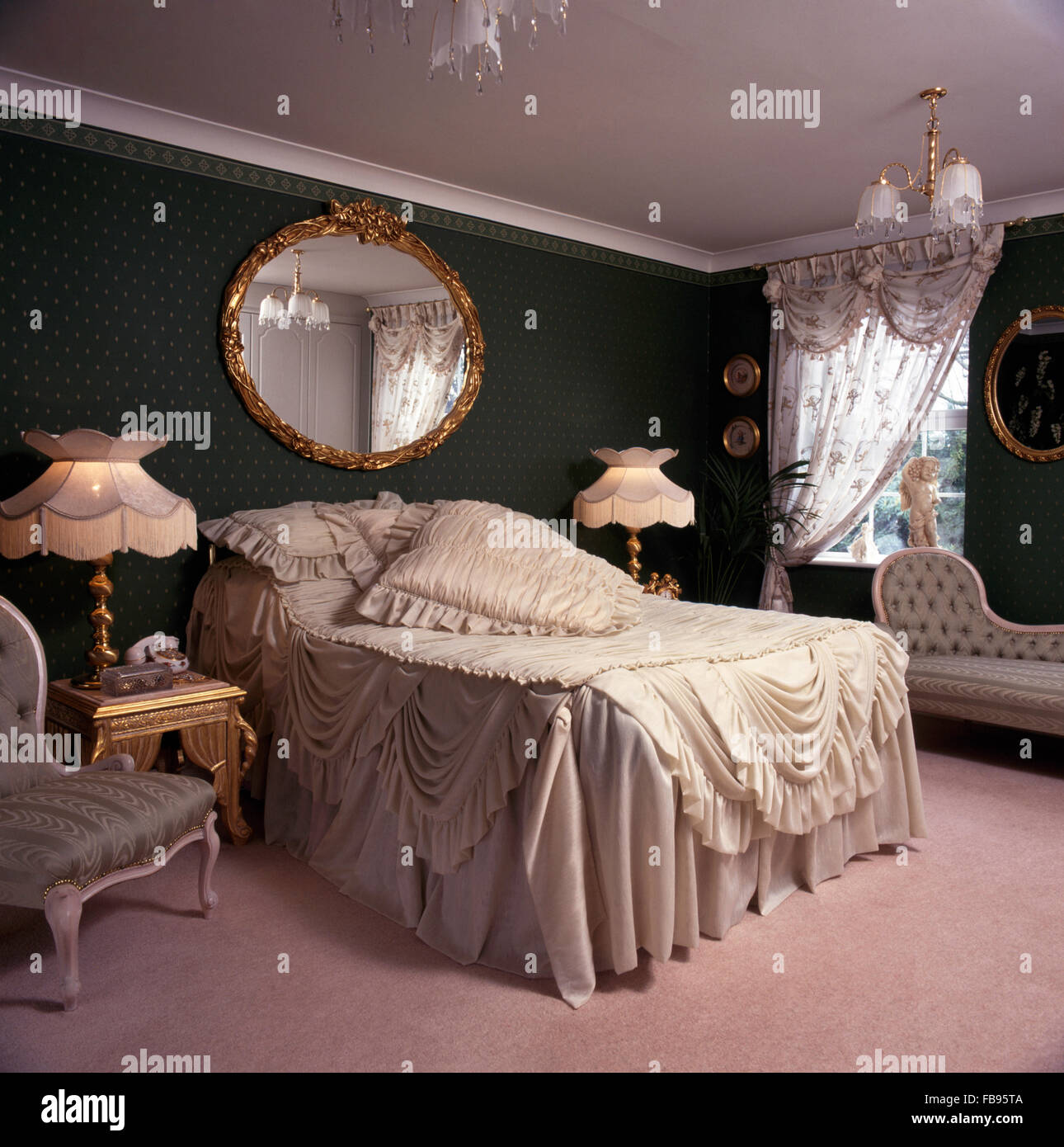 Large oval gilt mirror above bed with opulent, swagged cream chiffon