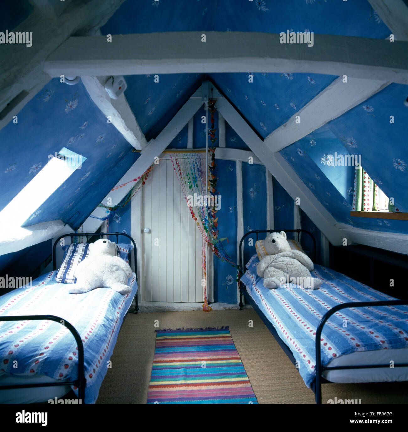 Toy polar bears on twin metal beds in children's bright blue attic ...