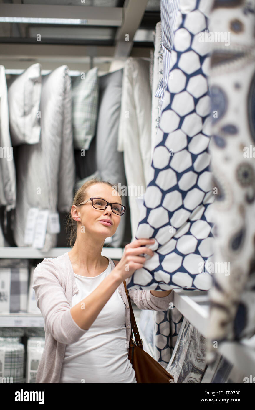 Pretty, young woman choosing the right sheets for her bed in a modern home furnishings store Stock Photo