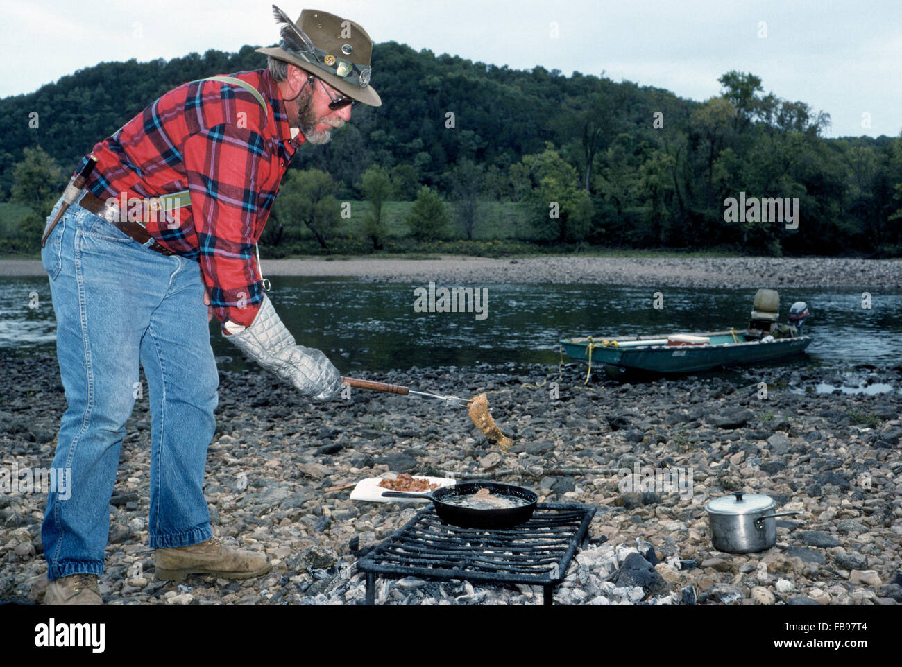 Professional fishing guide Hank Wilson panfries just-caught trout at the river's edge to serve to his fishing guests staying at Gaston's White River Resort in Arkansas, USA. Stock Photo