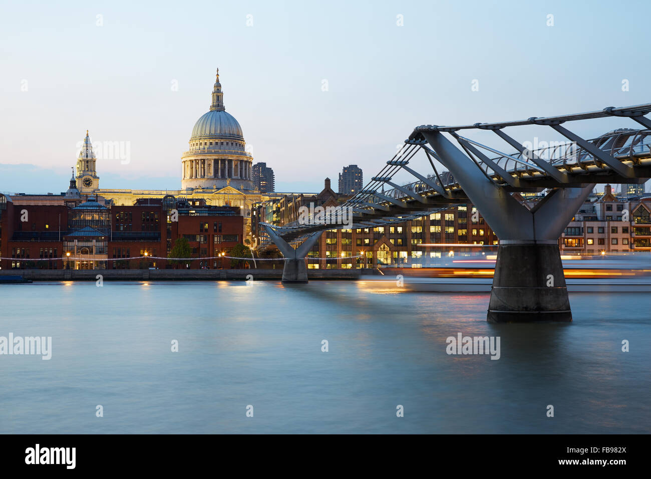 St Paul's cathedral and Millennium bridge in London in a clear evening, boat passing Stock Photo