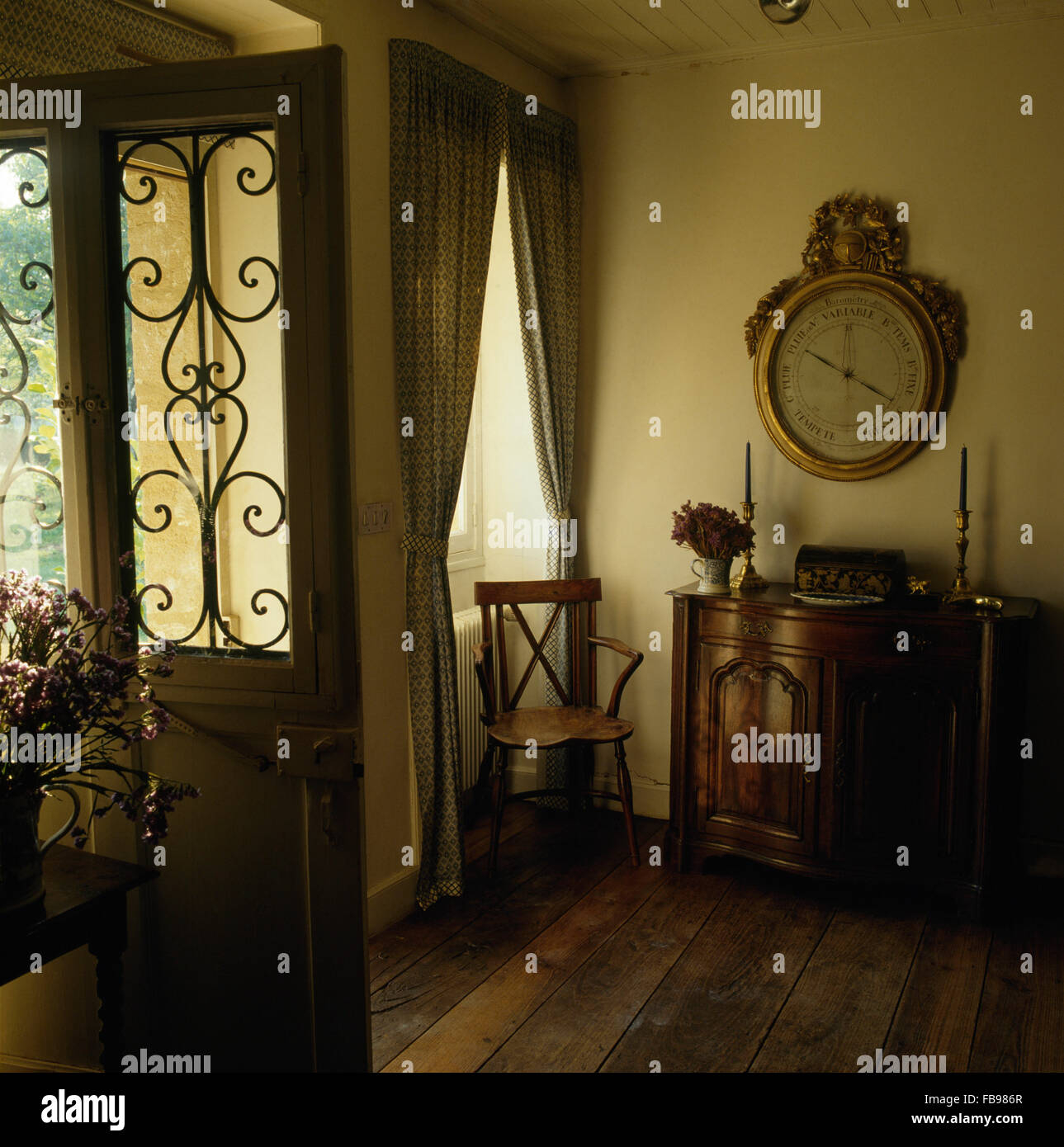 Large antique barometer above antique cupboard in traditional hall with wooden flooring and a half glazed door with a grille Stock Photo