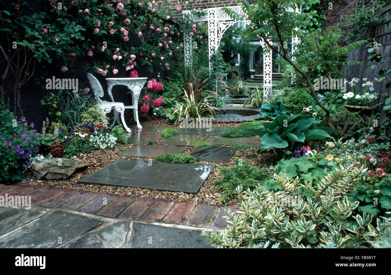 White wrought iron table and chair on terrace in townhouse garden Stock