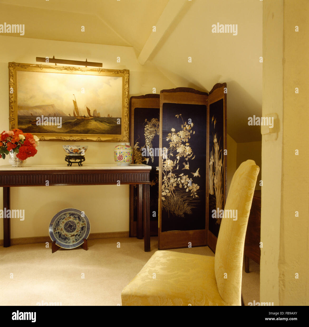 Large painting above console table in eighties hall with an antique folding screen and an