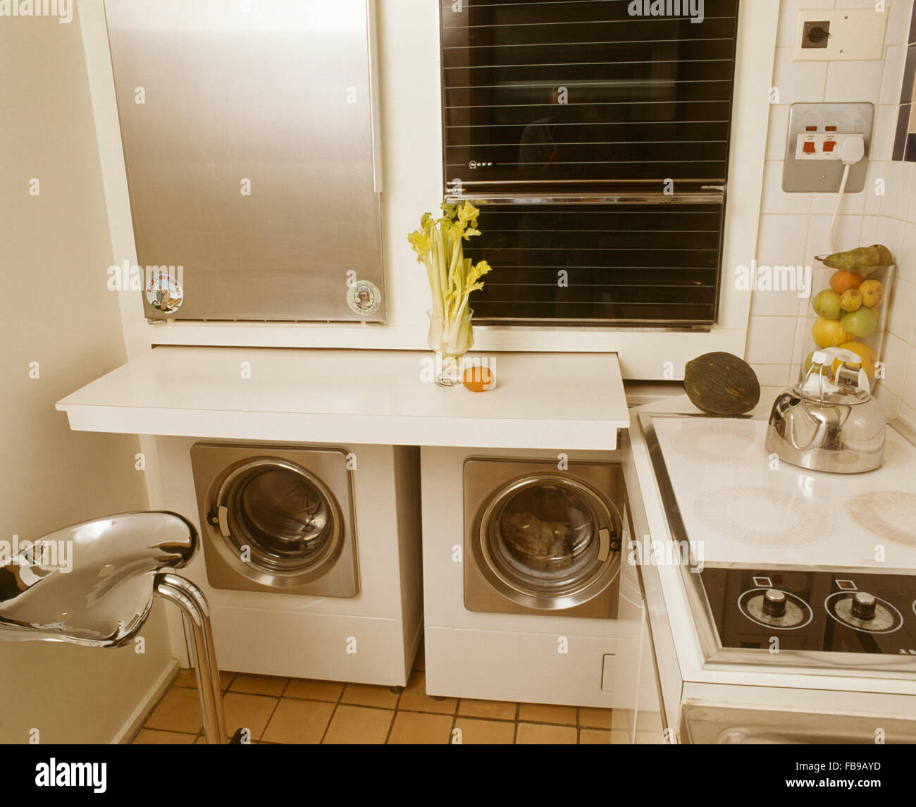 Wall mounted oven above washing machine and dryer in small seventies kitchen Stock Photo