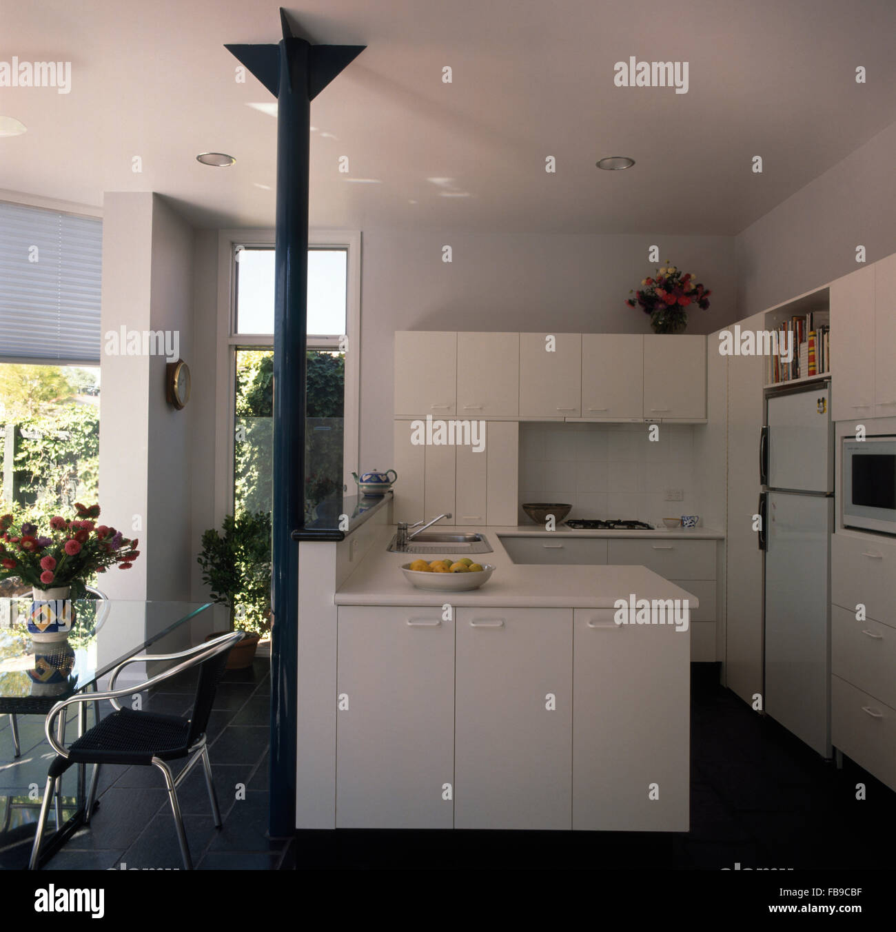White nineties architectural kitchen with a gray metal pillar and slate flooring Stock Photo