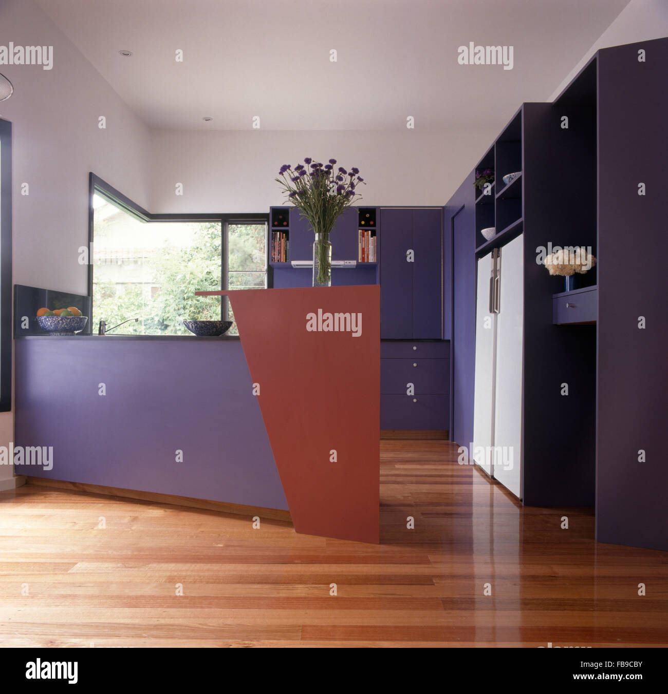 Wooden flooring in mauve and white kitchen with an angular peninsular unit Stock Photo