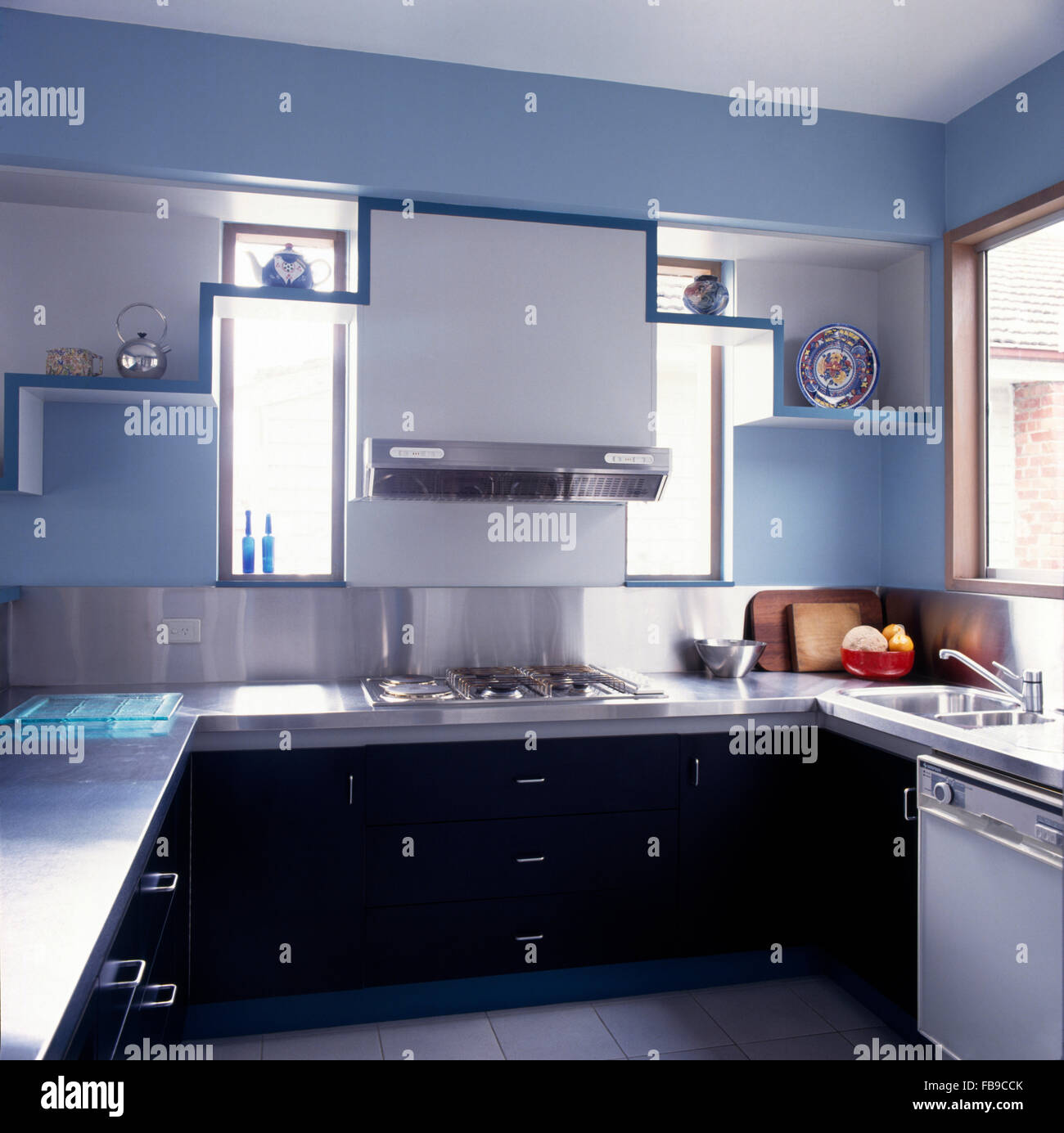Stainless steel extractor above hob in modern blue kitchen Stock Photo