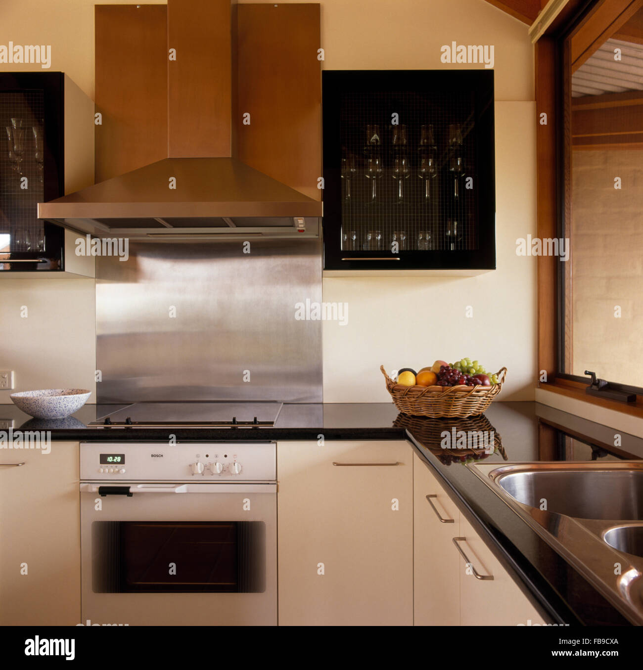 Stainless steel extractor and splash back above oven in modern kitchen Stock Photo