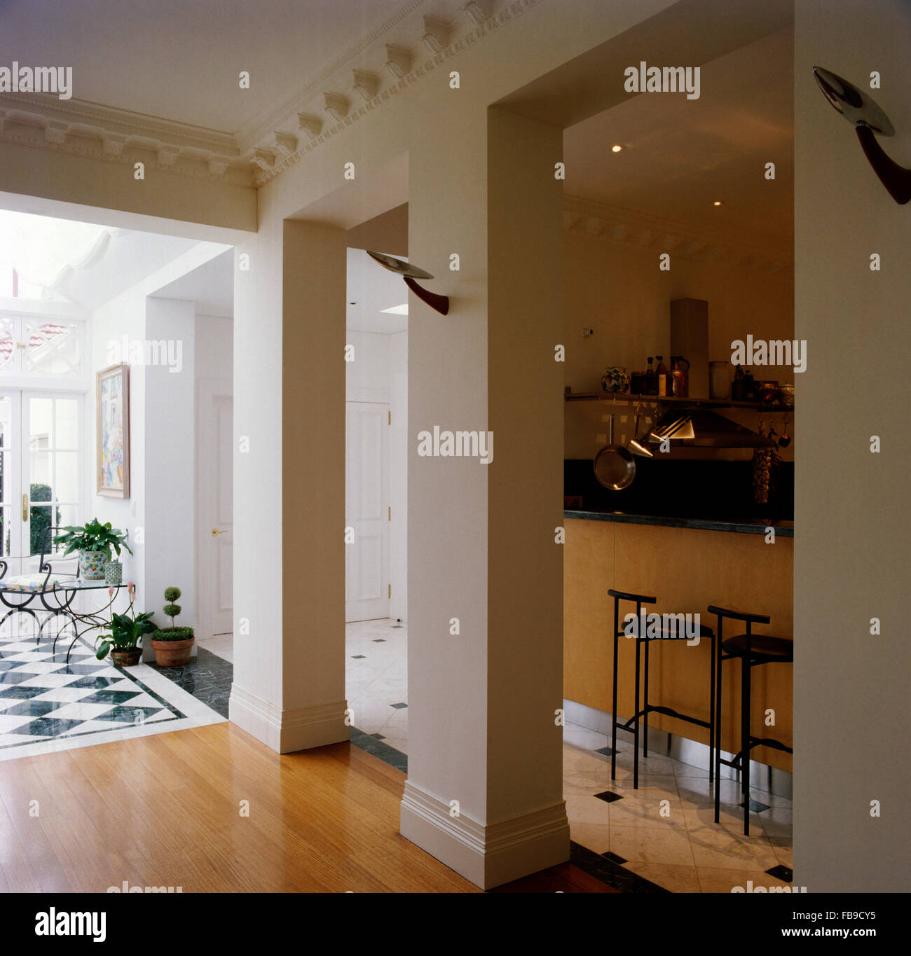 Angular Pillars Dividing Hall From Kitchen With Black Stools At