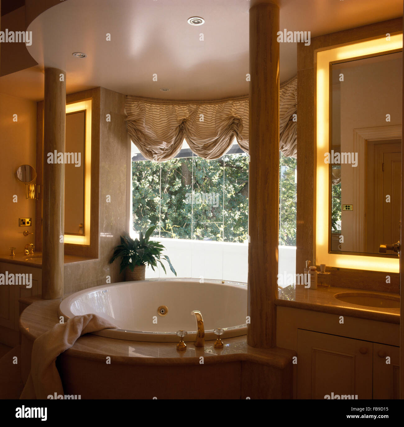 Striped festoon blind above spa bath in nineties bathroom with integral lighting on mirrors Stock Photo