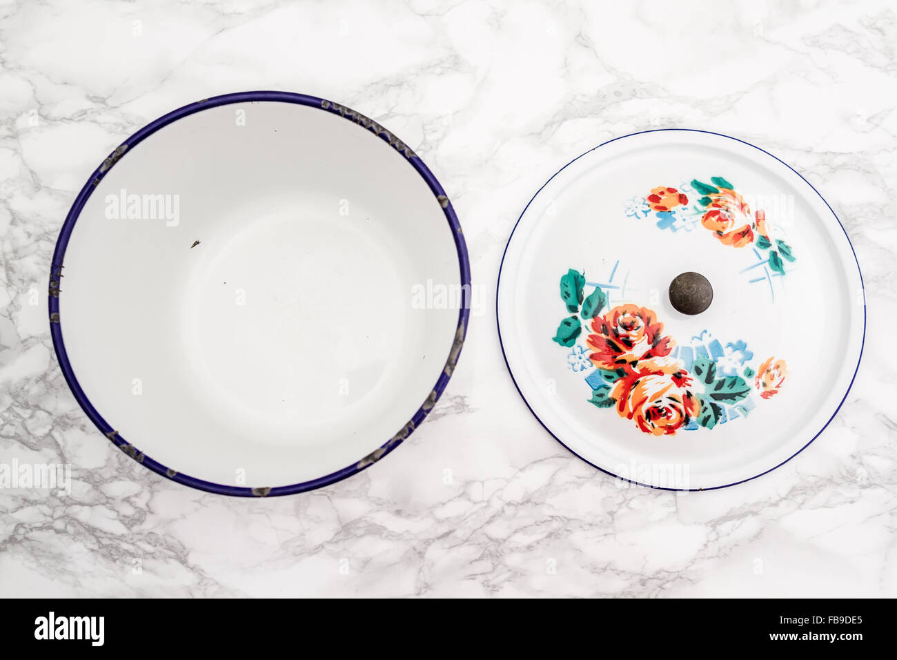 Empty white vintage enamel saucepan with flower design on white marble