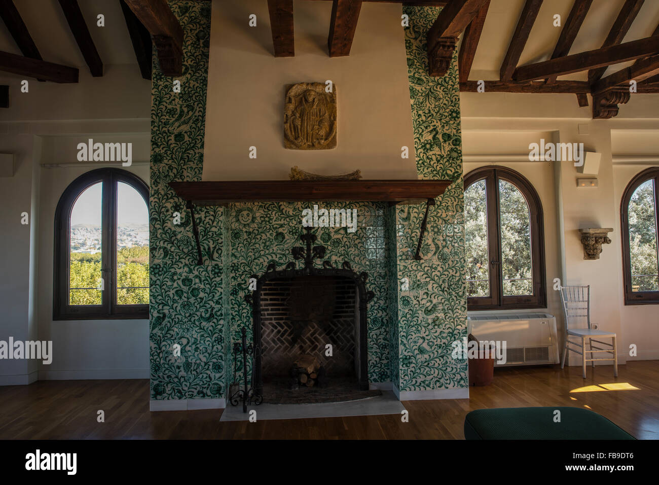 Spanish dining room with fireplace hearth and Spanish ceramic tile surround with wood beam ceiling and wooden floor. Stock Photo