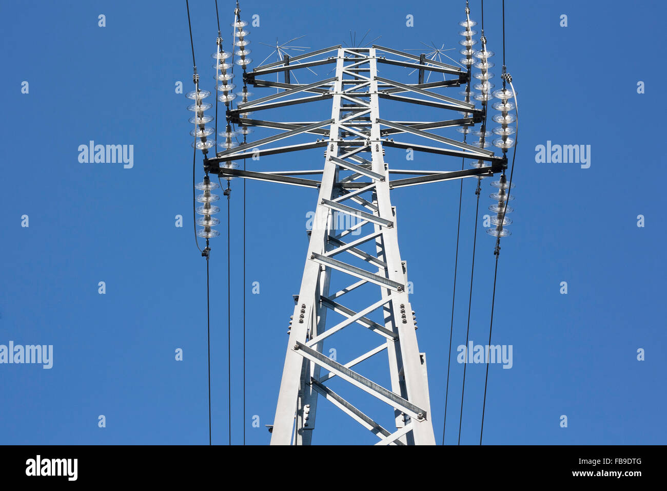 High voltage power pylons against blue sky. Low view Stock Photo - Alamy