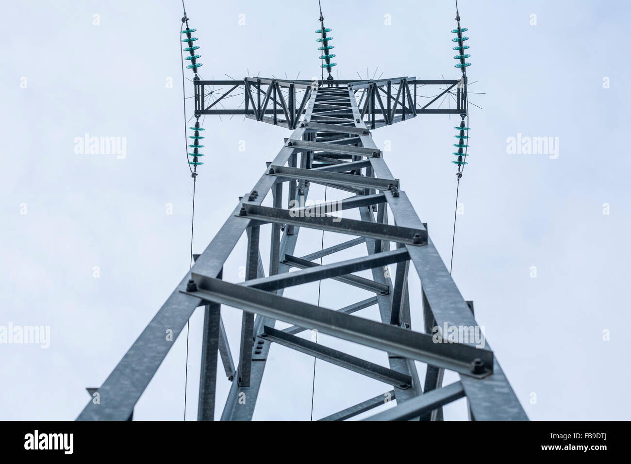 High voltage power pylons against blue sky. Low view Stock Photo - Alamy